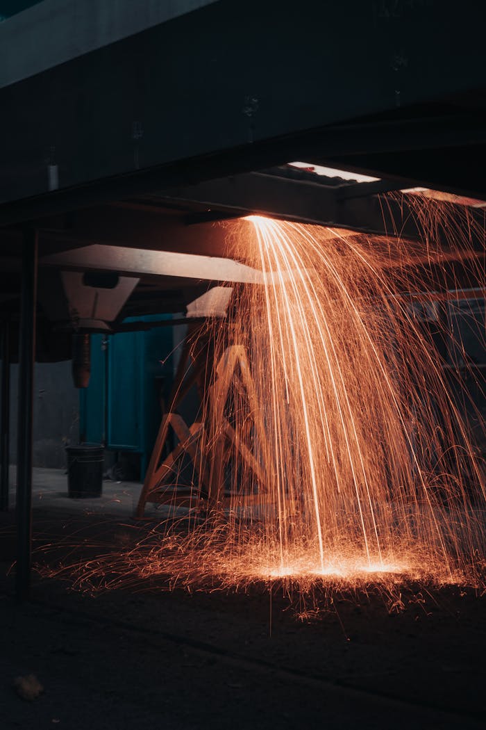 Intense sparks cascade down in an indoor industrial workshop, creating a captivating scene.